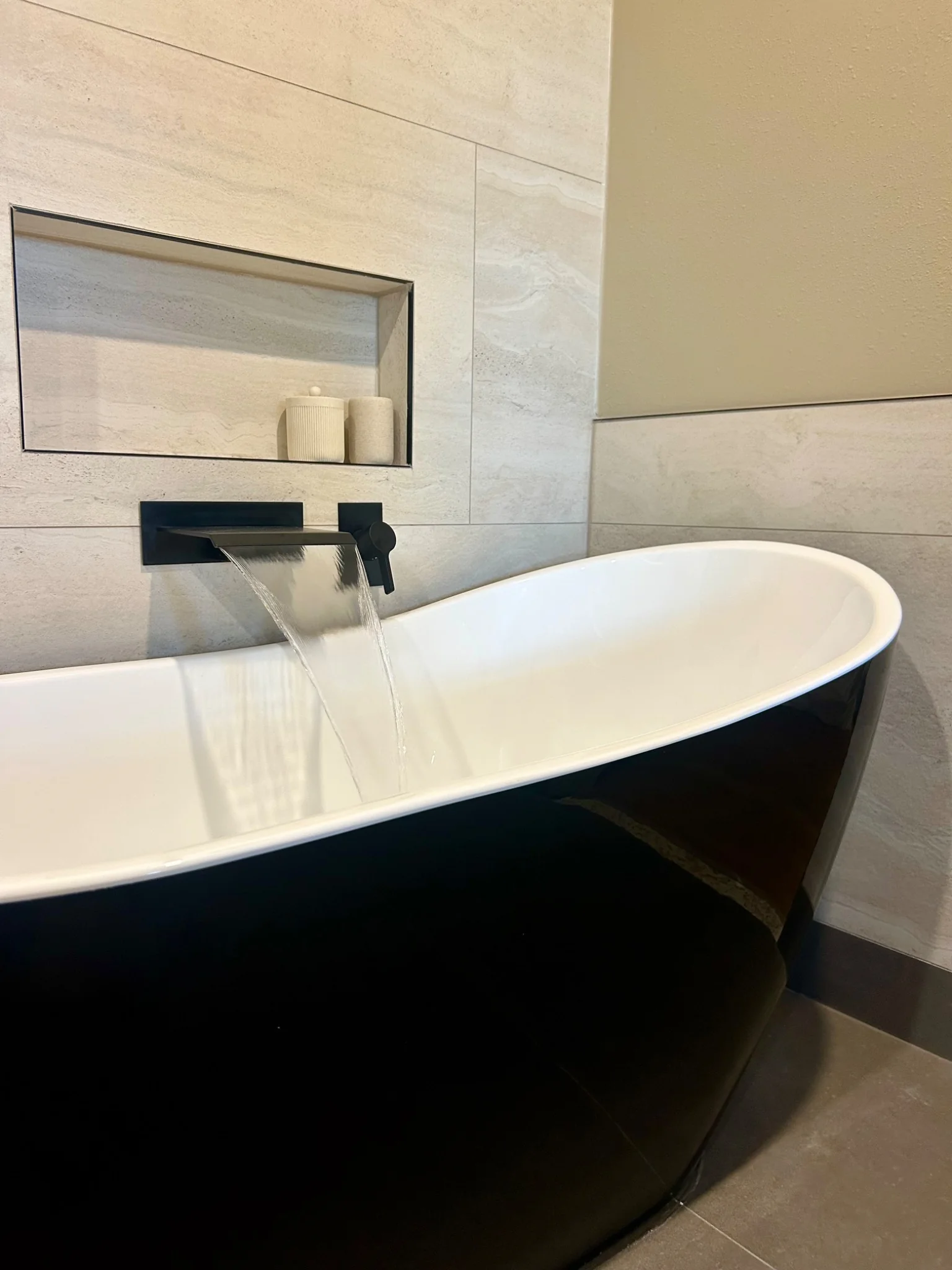 Black soaking tub with water running